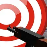 Κόκκινος και λευκός στόχος με μαύρο όπλο σε πέτρινο υπόβαθρο