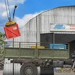 Ένα λευκό φορτηγό μπροστά από αποθήκη ενώ γερανός μεταφέρει κόκκινο κιβώτιο
